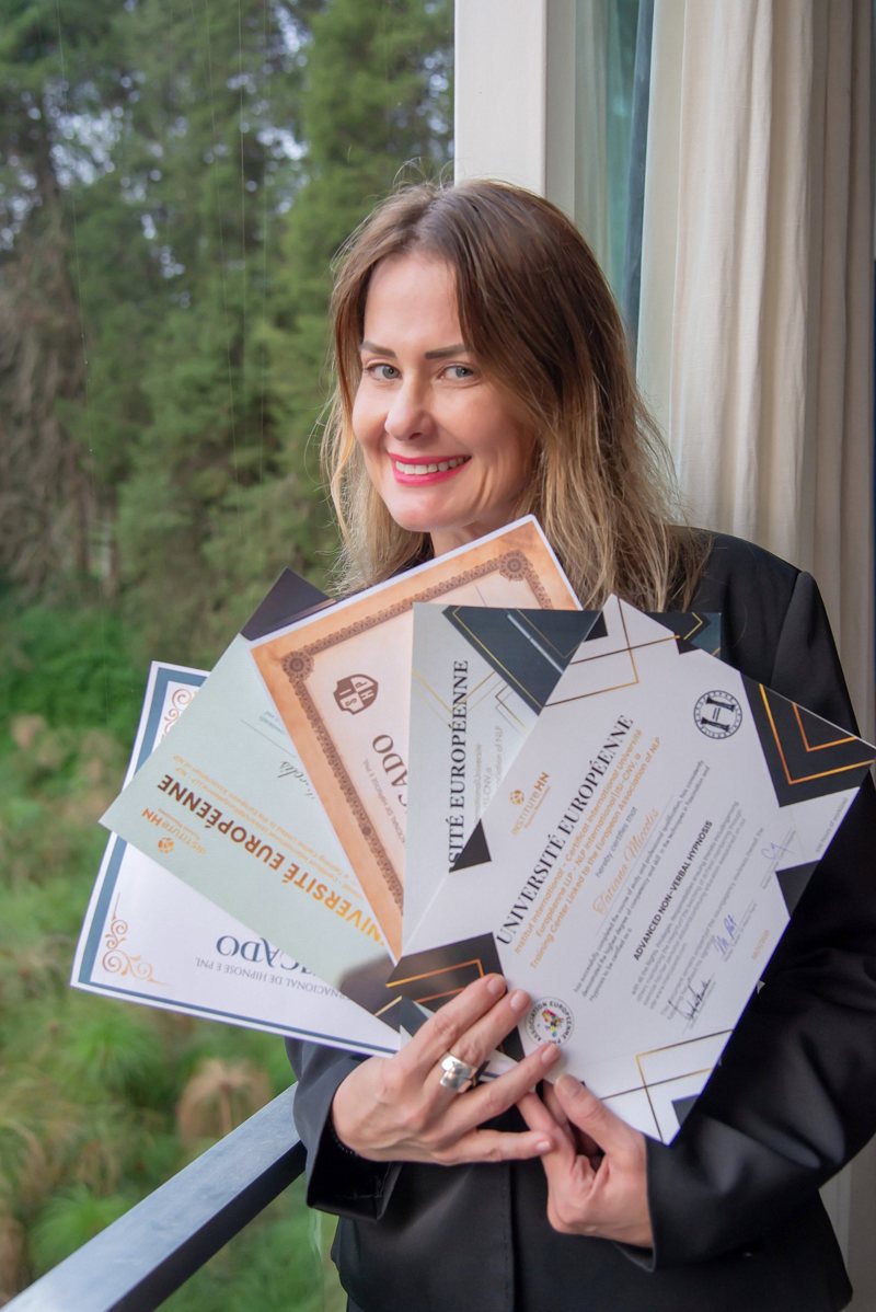 Tatiana sorrindo e segurando seus certificados de hipnose