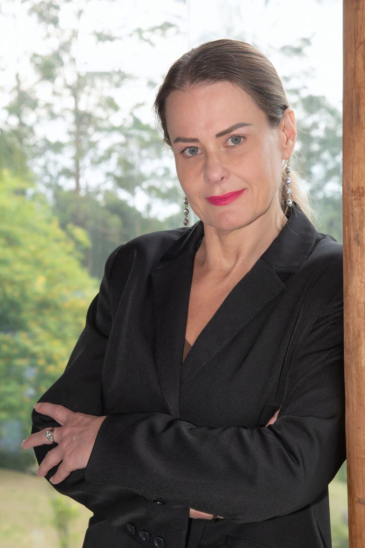 Tatiana de blazer preto, braços cruzados